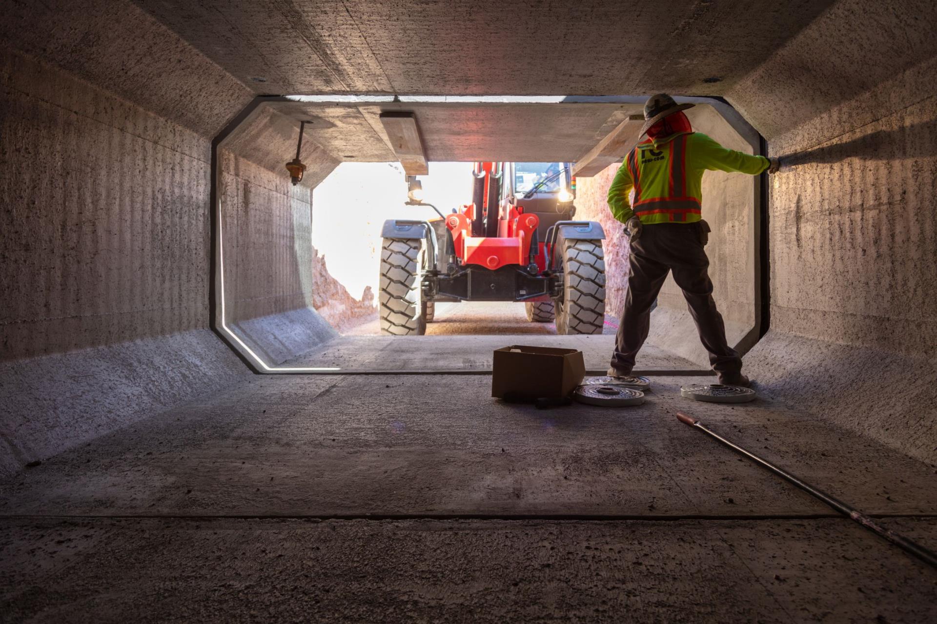 Construction worker is inside a reinforced concrete box, while construction loader moves the boxes.